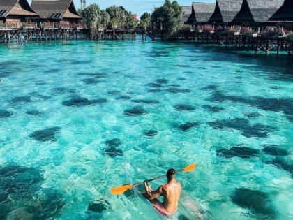 En mand i kajak med glasbund langs Sipadan Kapalai Dive Resort i Semporna, Sabah, Malaysian Borneo